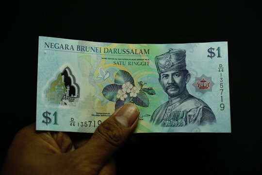 1 BND, one Brunei Darussalam Dollar money, was held by businessman, money concept isolated on black background