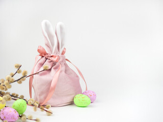 Fototapeta na wymiar Pink baggie with bunny ears, eggs and willow trees on a White background. The concept of Easter, a gift