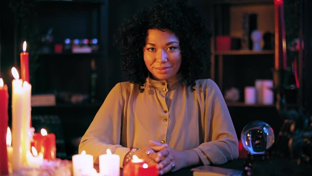 Friendly crystal gazer smiling on camera, inviting for fortunetelling session