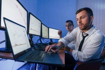 Making profit. Two stock traders working in the office with exchange technology