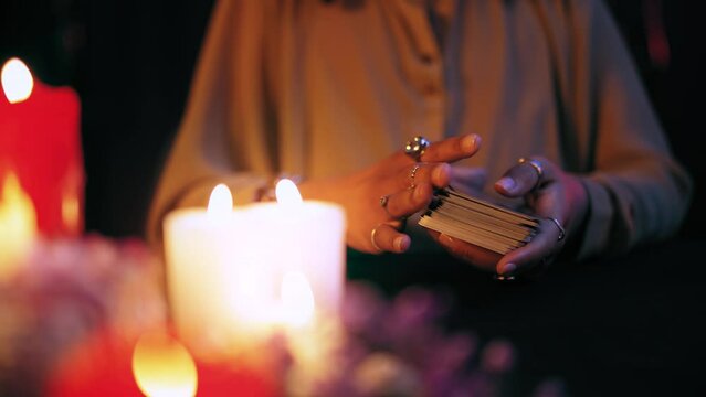 Crystal-gazer shuffling tarot cards in candle light, ritual to predict future