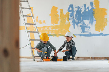 Blue and yellow colored background. Two boys painting walls in the domestic room