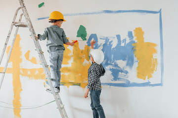 Two boys painting walls in the domestic room
