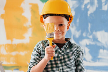 Peace in Ukraine. Blue and yellow colors. Little boy painting walls in the domestic room