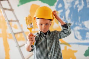 Blue and yellow colors behind. Conception of Ukraine and peace. Little boy painting walls in the...