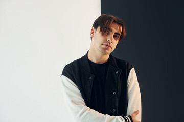 Looking into the camera. Young man is in the studio with white and black walls