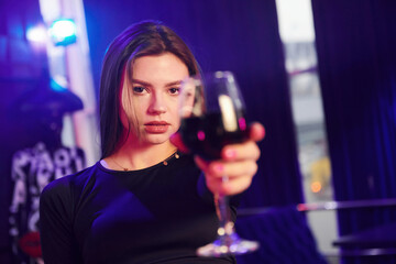 Woman standing in night club and holding glass with drink