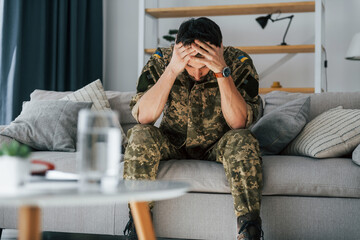 On the sofa. Post traumatic stress disorder. Soldier in uniform sitting indoors