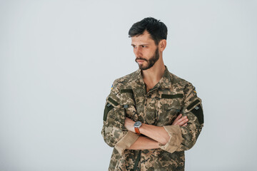 Soldier in uniform is standing indoors against white wall