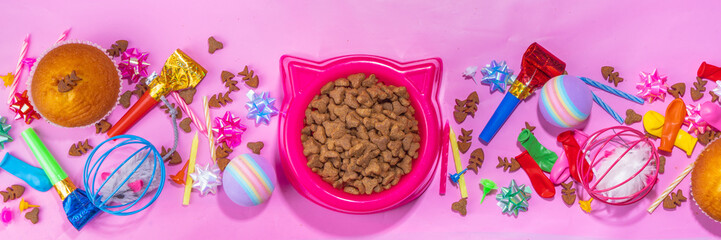 Pet cat happy birthday background with set different cats and kitty snack, food and toys, cat muzzle shape bowl, birthday cupcakes with happy birthday candles, accessories. Flatlay on pink background