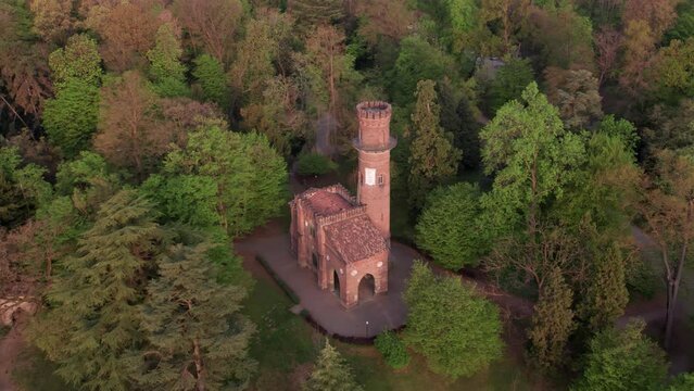 The small tower inside the Park of Monza surrounded by trees, aerial parallax panoramic view.