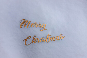inscription in gold letters on the snow, Merry Christmas. winter holidays