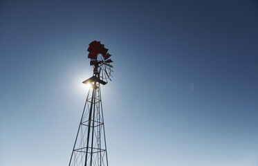 View of windmill that is against clear blue sky with sunlight