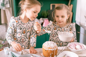 happy family candid little kids sisters girls together have fun ready springtime Easter holiday at home in kitchen decorating table and Easter cakes bakery sweet icing and candy for lunch or dinner