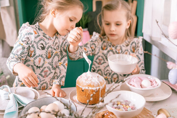 happy family candid little kids sisters girls together have fun ready springtime Easter holiday at home in kitchen decorating table and Easter cakes bakery sweet icing and candy for lunch or dinner
