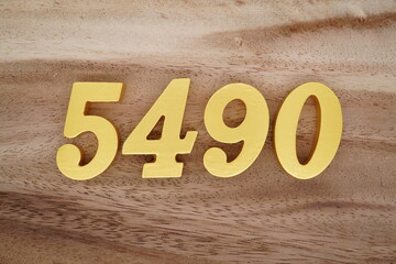 Golden Arabic numerals on a real brown and white wooden floor number 5490