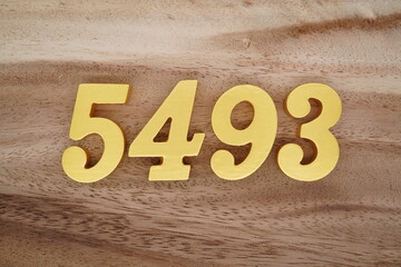 Golden Arabic numerals on a real brown and white wooden floor number 5493