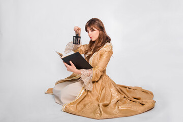 Full length portrait of a young woman in a puffy gold dress in the rococo era, posing while sitting...