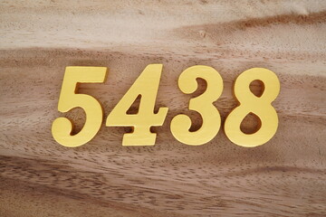 Golden Arabic numerals on a real brown and white wooden floor number 5438