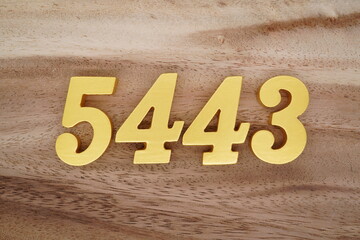 Golden Arabic numerals on a real brown and white wooden floor number 5443