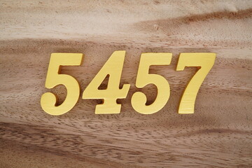 Golden Arabic numerals on a real brown and white wooden floor number 5457