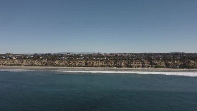 A beautiful aerial drone shot, drone flying towards the coast and a neighborhood with mountains in the background, Carlsbad State Beach - California