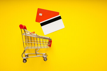 Credit cards with shopping cart on yellow background. Shopping online concept