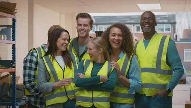 Portrait of multi-cultural team wearing hi-vis safety clothing working in modern warehouse - shot in slow motion