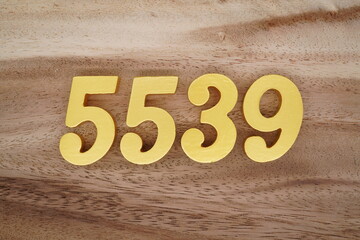 Golden Arabic numerals on a real brown and white wooden floor number 5539