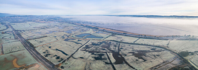 Misty Sunrise over hoarfrosted Wetlands and meadows, RSPB Exminster and Powderham Marshe from a drone, Exeter, Devon, England
