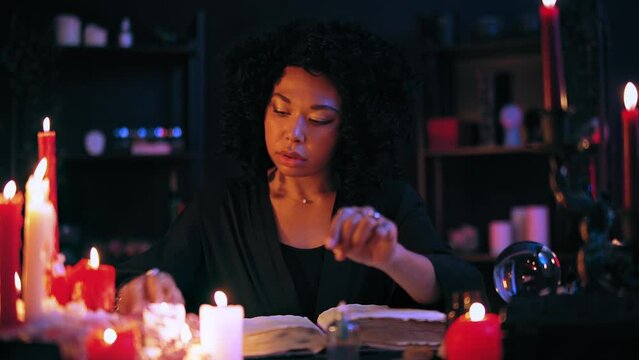 Wise witch reading old spell book, preparing ingredients for magic potion