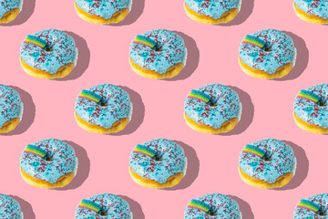 A repeating pattern of blue donuts with a rainbow on a pink background
