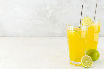 Fresh lemonade from oranges, limes and lemons in glasses on a light background. Horizontal orientation, copy space.