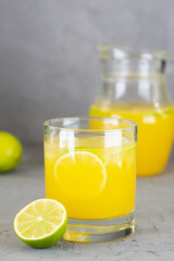 Fresh lemonade from oranges, limes and lemons in a glass on a gray background.