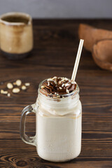 Vegan milkshake with nuts and caramel in a mug on a wooden table.