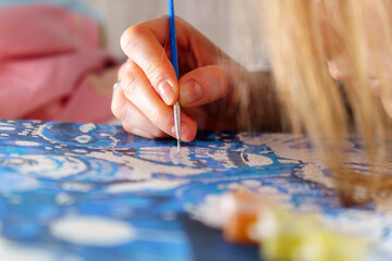 Naklejka premium Close Up of woman Artist Hand, Holding Paint Brush and Drawing Oil Painting. Selective focus