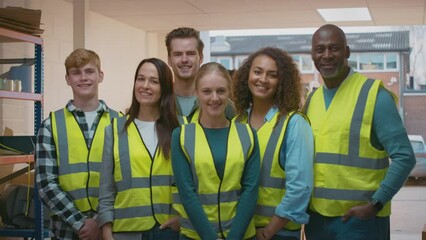 Portrait of multi-cultural team wearing hi-vis safety clothing working in modern warehouse - shot in slow motion