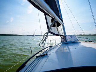 Obraz premium view on a sailing boat bow and sail sailing on a lake in a windy sunny day