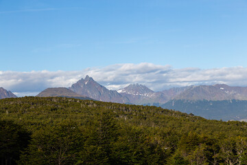 Fototapeta premium Mountain peaks covered with snow and hills with grass and vegetation