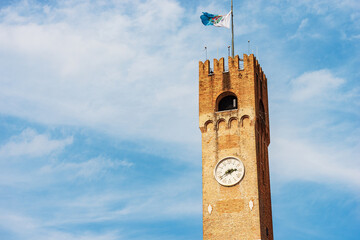 Close-up of the ancient medieval Civic Tower in Treviso Downtown, 1218, with the flag of the city....