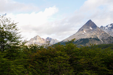 Fototapeta premium Mountain peaks covered with snow and hills with grass and vegetation