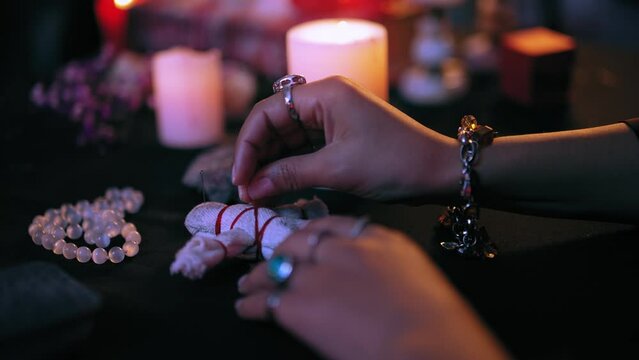Evil witch hands piercing voodoo doll with pins, dark magic, occult ritual