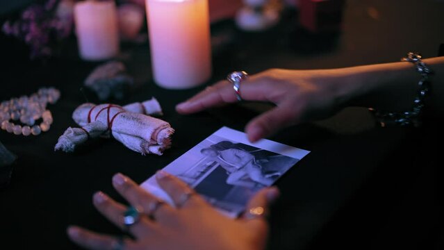 Witch performing occult ritual over man's photo, pushing needles in voodoo doll