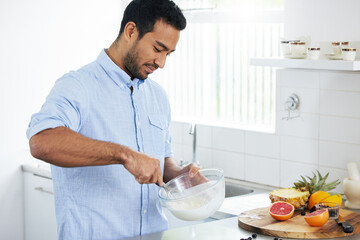 Im whipping up something delicious and nutritional. Shot of a man making himself a smoothie at home.