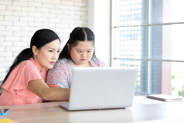 down syndrome teenage girl and her teacher using laptop computer together on a table
