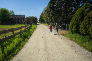 Two young girls are walking a country road in the summer