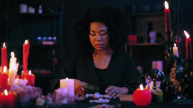 Evil witch pushing pins in voodoo doll, putting black spell on victim, occultism