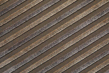 The texture of a natural beige cotton corduroy fabric with light stripes, located diagonally. The ridges of the corduroy on the diagonal
