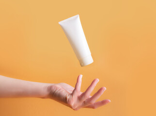 Woman's hand with cream on orange background with palm up