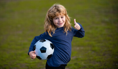 Soccer kid boy playing football. Child boy play football on outdoor field show thumbs up success sign . Children score goal at soccer game. Fan sport boy player hold soccer ball.